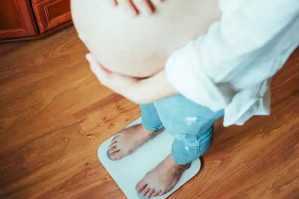 Image of woman weighing herself and experiencing weight gain through pregnancy Chard